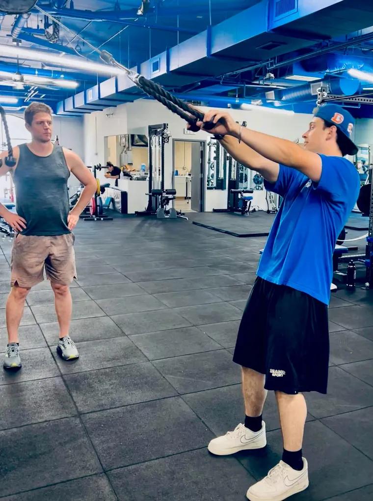 Boston Adams demonstrating a cable rope row to a client during a session