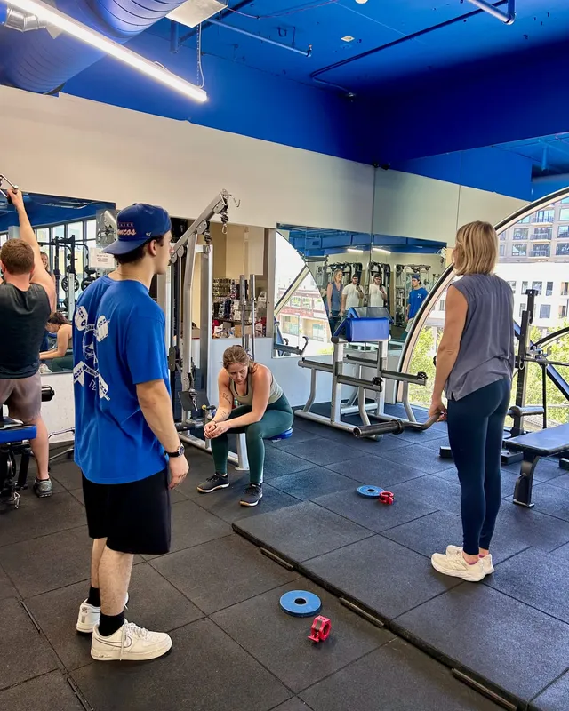 Boston Adams coaching squat form at Ally Fitness Boston Adams coaching two clients through goblet-squat form