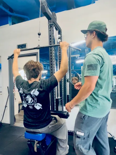 Boston Adams, NASM-certified personal trainer and founder of Ally Fitness, coaching a client through lat-pulldown form