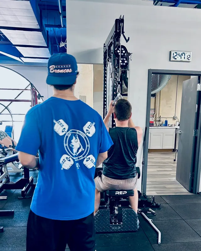 Boston Adams supervising a client's lat-pulldown set during a training session